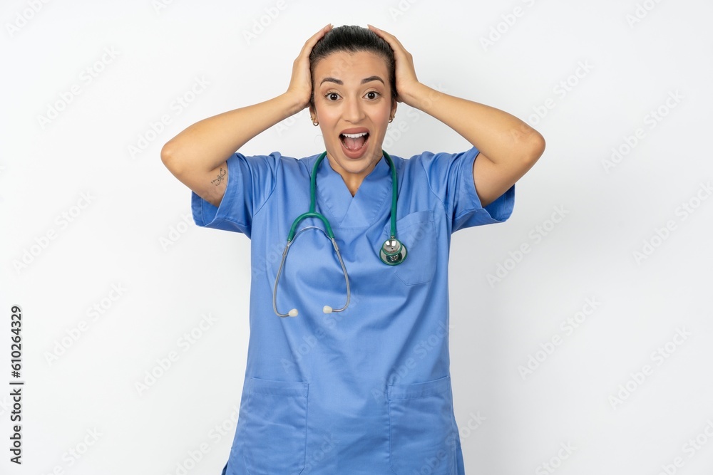 Cheerful overjoyed Beautiful doctor woman standing over white studio background reacts rising hands over head after receiving great news. Cheerful overjoyed Beautiful doctor woman standing over white studio background reacts rising hands over head after receiving great news.