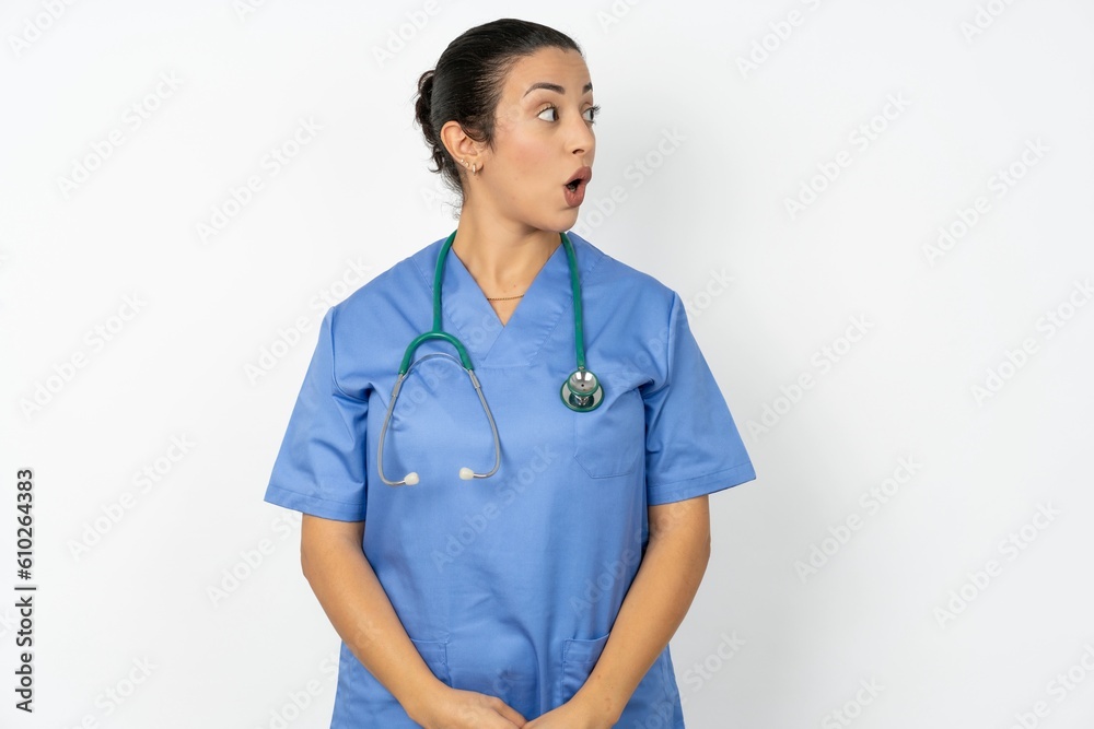 Shocked Beautiful doctor woman standing over white studio background look empty space with open mouth screaming: Oh My God! I can't believe this. Shocked Beautiful doctor woman standing over white studio background look empty space with open mouth screaming: Oh My God! I can't believe this.