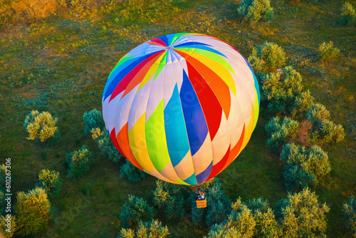 Hot air balloon is flying over land with trees at the morning photo