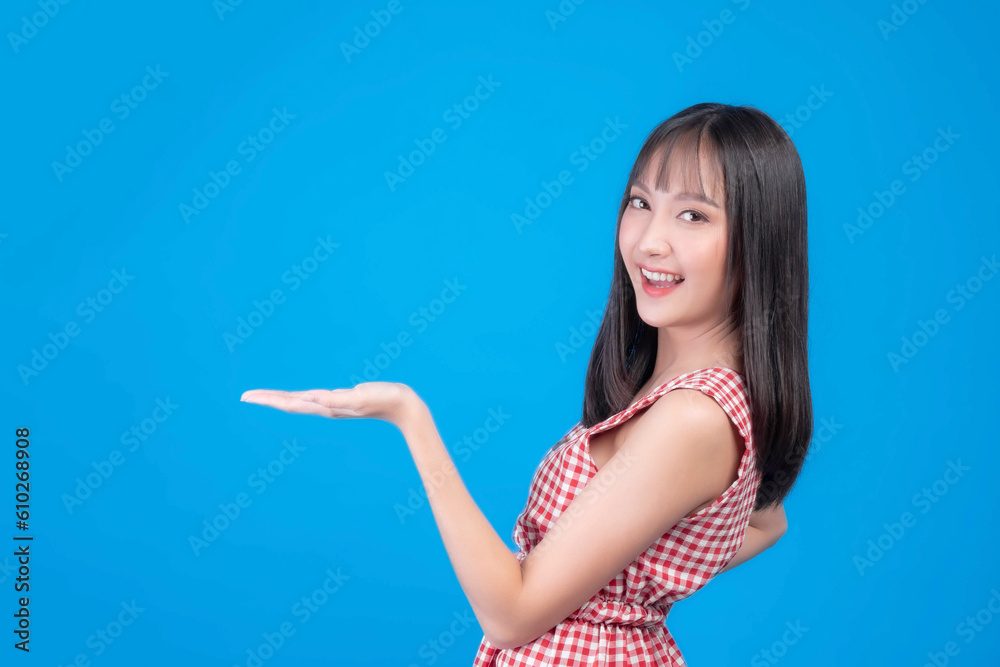 Beautiful beauty Asian woman cute girl with bangs hair style in red dress smile and posing her empty hands with copy space , blank space for advertising isolated on blue background Beautiful beauty Asian woman cute girl with bangs hair style in red dress smile and posing her empty hands with copy space , blank space for advertising isolated on blue background