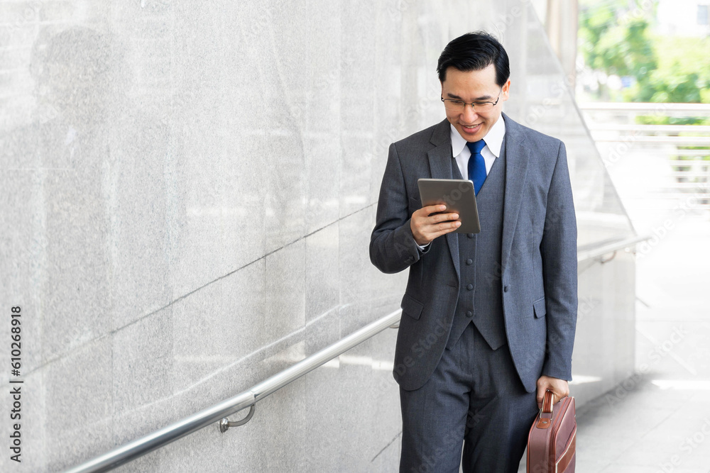 Portrait Asian business man business walking on business district ,senior visionary executives leader with business vision , tabled phone computer in hand Portrait Asian business man business walking on business district ,senior visionary executives leader with business vision , tabled phone computer in hand