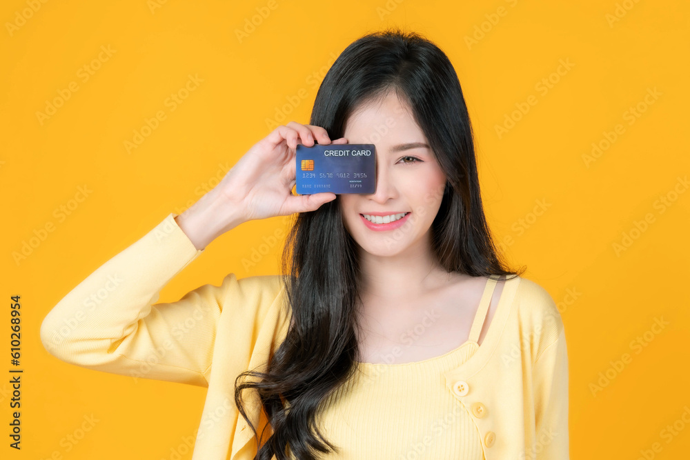 beautiful Asian young woman cute girl showing credit card for payment shopping online and - paying by credit card isolated on yellow background - online shopping e-commerce telemarketing beautiful Asian young woman cute girl showing credit card for payment shopping online and - paying by credit card isolated on yellow background - online shopping e-commerce telemarketing