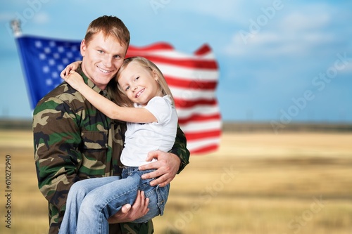 Military man carrying little child, american flag