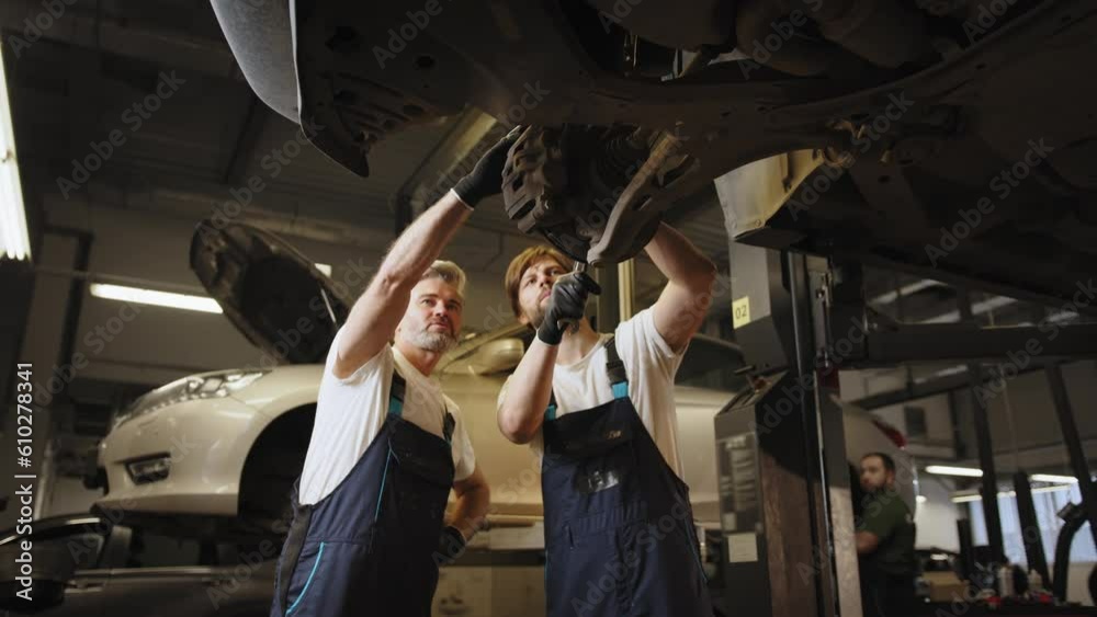 Workflow in a car workshop. Mechanic in work at the auto service. Family business concept. Workflow in a car workshop. Professional mechanic repairing a car in auto repair shop