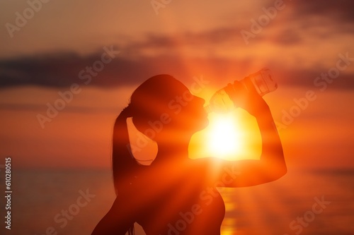 Silhouette of a person drinking water on sunset background