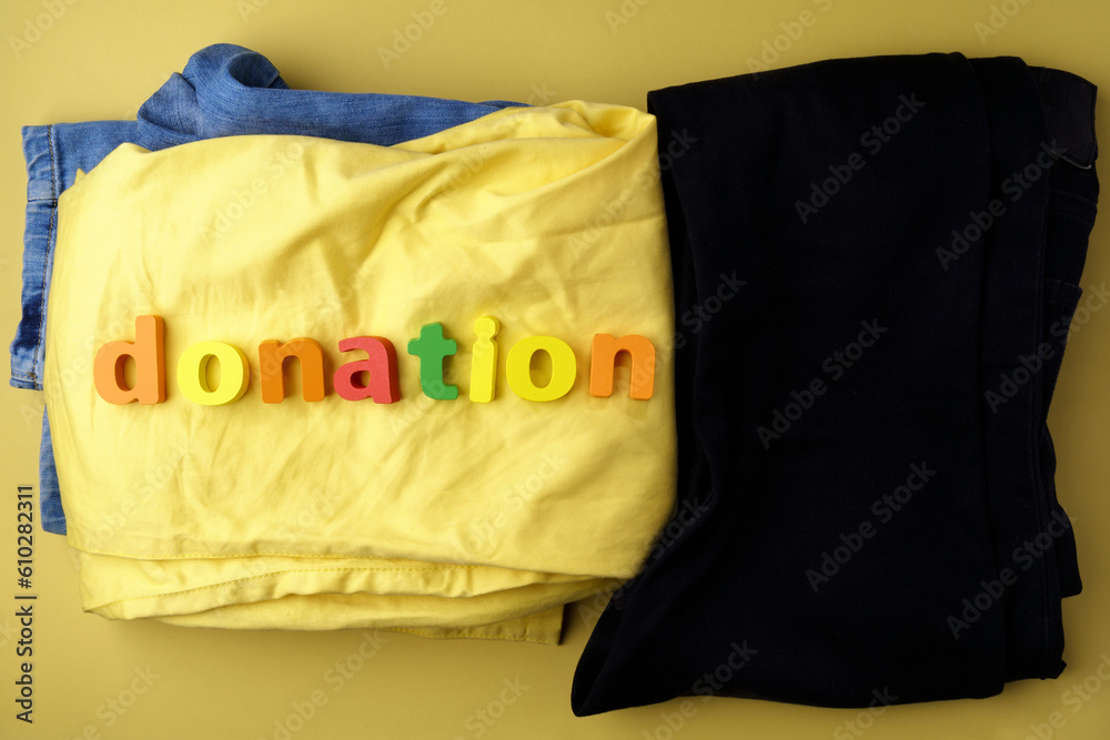 Clothes and an inscription: the donation is on it. Symbol of charity, yellow background