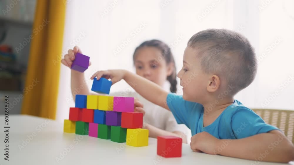 children in kindergarten play with blocks on the table by the window. education development children game concept. children play with blocks at home rejoice having. children play together at fun home children in kindergarten play with blocks on the table by the window. education development children game concept. children play with blocks at home rejoice having. children play together at fun home