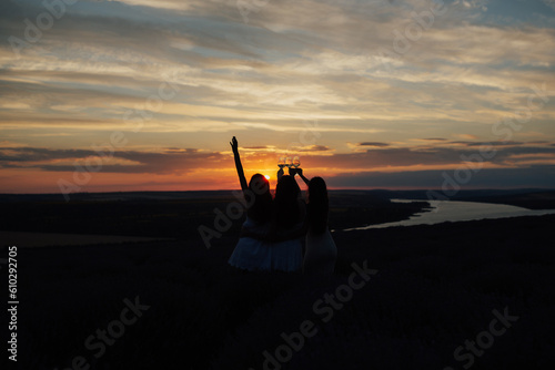 Obraz na płótnie Lovely ladies drinking wine in lavender violet field at sunset. Summer happy mood. Girlfriends relaxing on summer sunset with river on the background. w salonie