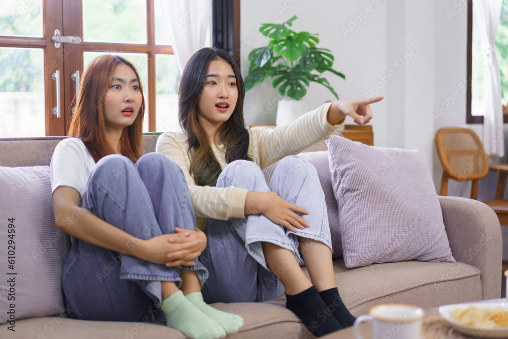 Obraz premium Activity at home concept, LGBT lesbian couple feel scared and pointing screen while watching movie