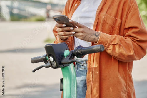 Unrecognizable woman using mobile phone to use a electric scooter