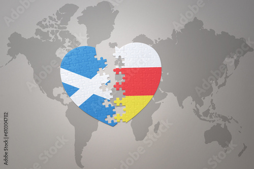 puzzle heart with the national flag of south ossetia and scotland on a world map background.Concept.