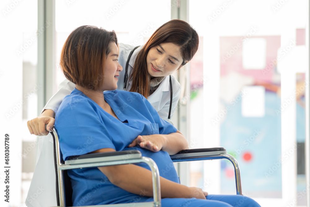 Obraz premium woman obstetrician doctor look holding hand to consoling encourage woman pregnant patient on wheelchair in hospital. woman doctor talk diagnosis treatment for mother pregnancy