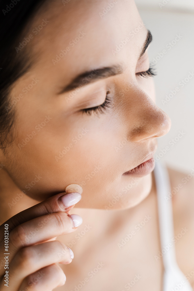 Applying acne round patch on cheek of girl close-up. Young woman using acne patches for treatment of pimple and rosacea. Facial rejuvenation cleansing cosmetology. Applying acne round patch on cheek of girl close-up. Young woman using acne patches for treatment of pimple and rosacea. Facial rejuvenation cleansing cosmetology.