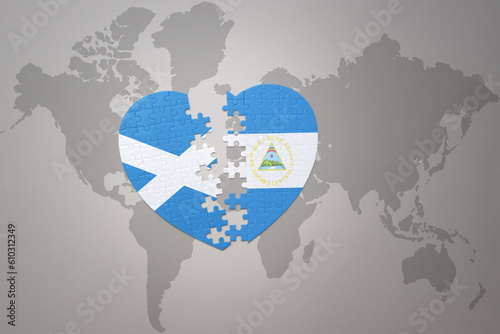 puzzle heart with the national flag of nicaragua and scotland on a world map background.Concept.