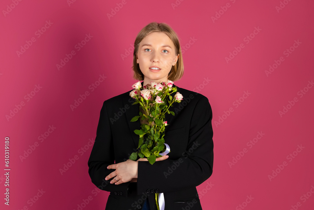 Beautiful tender young blonde hair girl in black blazer holds flowers. isolated on pink background. Beautiful tender young blonde hair girl in black blazer holds flowers. isolated on pink background.