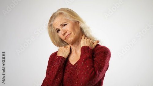 Tired upset middle aged woman suffering from neck pain. Portrait of exhausted unhappy elderly mature lady massaging muscles, feeling unwell at home, osteoarthritis ache concept.