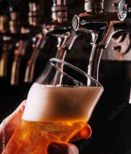 Close-up of barman hand at beer tap pouring a draught lager beer