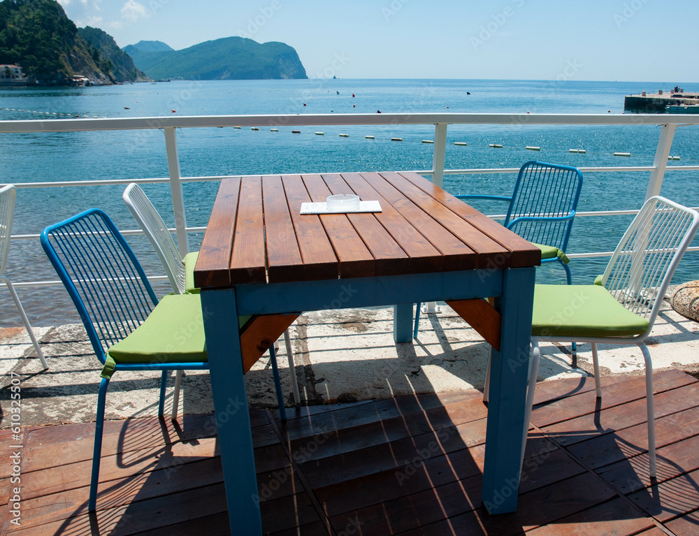 Wooden table on the terrace and chairs by the sea.