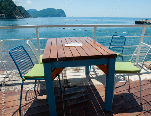 Wooden table on the terrace and chairs by the sea.