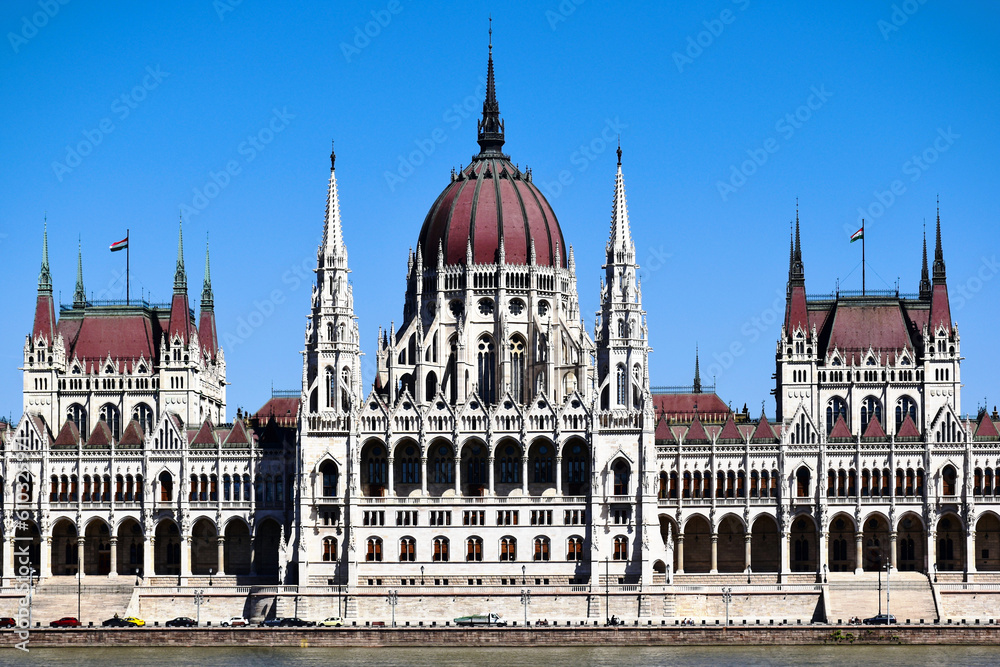 Fototapeta premium elevation detail of the neo gothic stone building along the Danube river. arched windows. tall tower with cupola. famous historic landmark building. popular tourist destination. blue sky. 