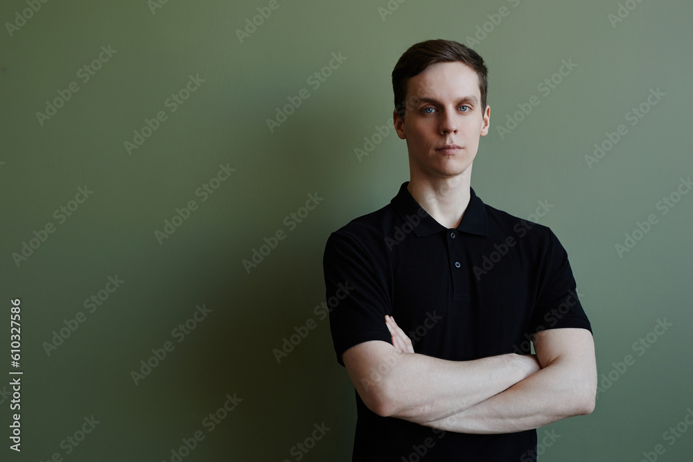 Minimal portrait of confident young man looking at camera against green, copy space Minimal portrait of confident young man looking at camera against green, copy space