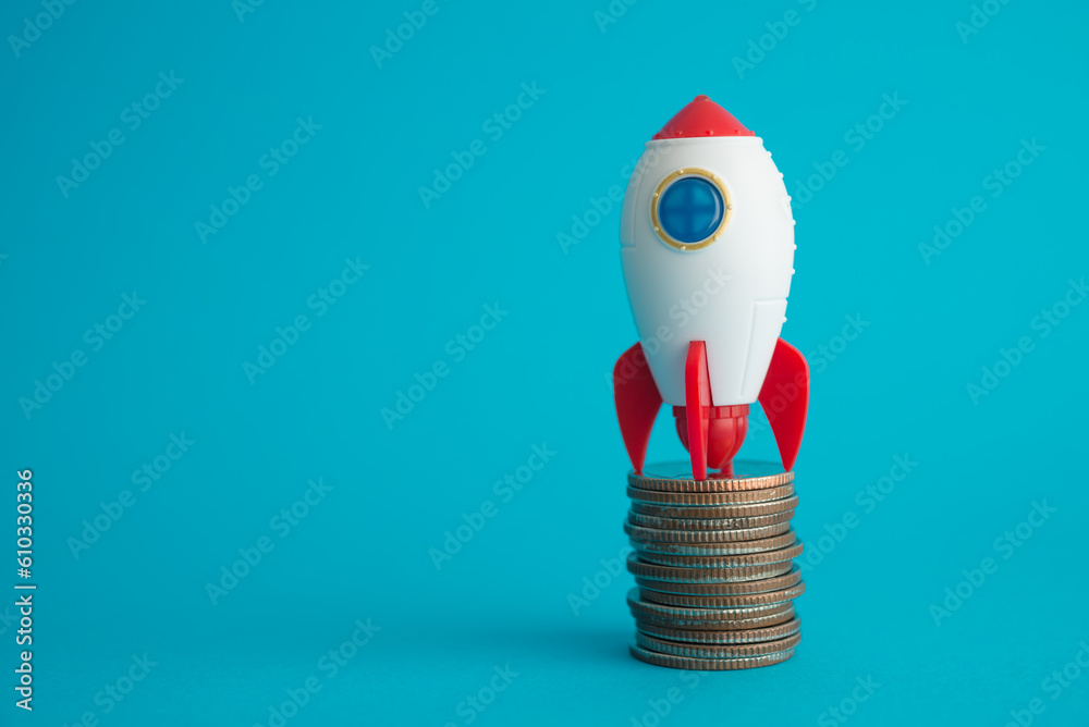 Rocket rising up on stack coins with blue background copy space. Business strategy, financial, stock market, investment, startup concept. Fast profit growth and success target. Rocket rising up on stack coins with blue background copy space. Business strategy, financial, stock market, investment, startup concept. Fast profit growth and success target.