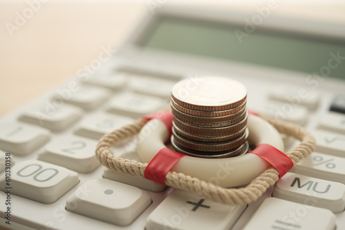 фотографія Stacked coins in red lifebuoy or lifebelt on calculator background copy space