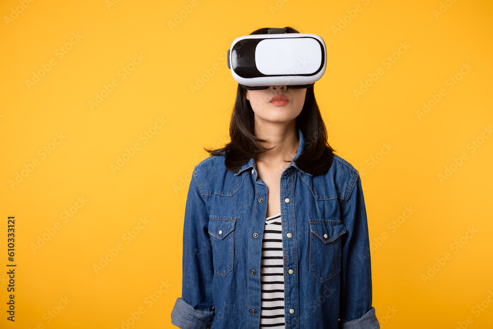 Young asian woman get experienced wearing virtual reality headset game entertainment isolated on yellow background. Winner of cyber future video game concept. Young asian woman get experienced wearing virtual reality headset game entertainment isolated on yellow background. Winner of cyber future video game concept.