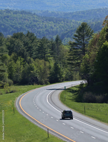 solo car drives on a windy road in the mountains of new england (road, grass, trees, hills)