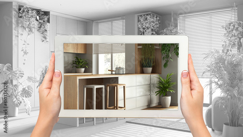 Augmented reality concept. Woman hands holding tablet with AR application used to simulate furniture and design products in total white background, urban jungle kitchen