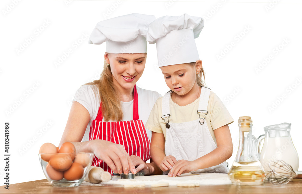 Mother and little girl making a cake together - spreading the filling Mother and little girl making a cake together - spreading the filling