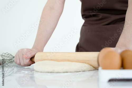 Woman kneading dough with a rolling pin.
