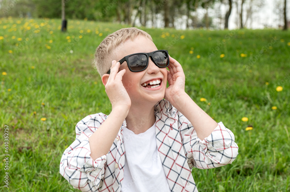 Cute boy put on colorblind sunglasses and laughs. Snow-white teeth in a boy in sunglasses Cute boy put on colorblind sunglasses and laughs. Snow-white teeth in a boy in sunglasses