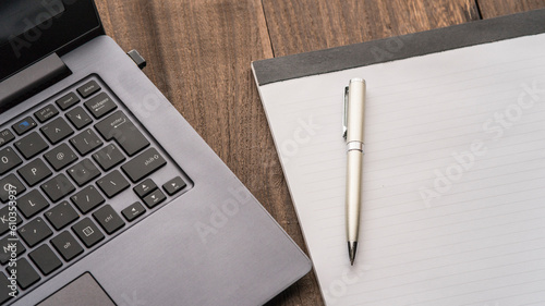 Notebook computer, pen  and notepad on the wooden table. photo