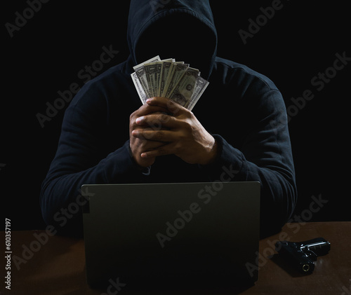 Hacker spy man hands wearing a black shirt, sitting on a chair and a table, is a thief, holding money, counting the amount obtained from hijacking or robbing, in a pitch-black room.