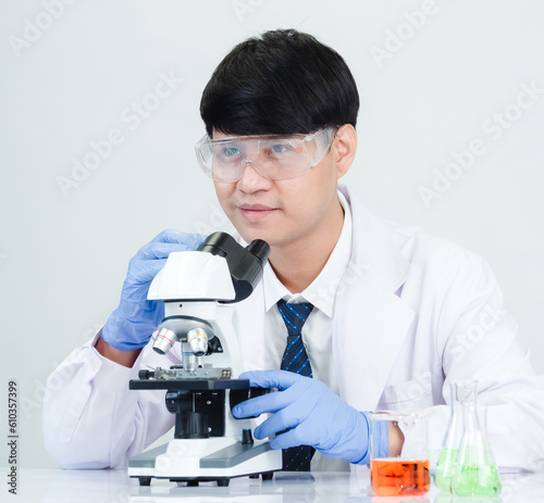 Asian man student scien Wearing a doctor's gown in the lab looking hand at chemist. caused by mixing reagents in scientific research laboratories with test tubes and microscope on the table photo