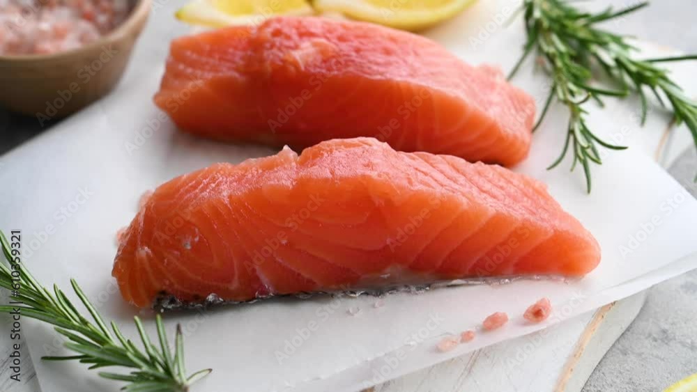 Raw salmon fillet steak with lemons and fresh herbs, copy space. Raw salmon fillet steak with lemons and fresh herbs, copy space.
