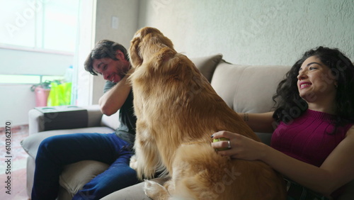 Happy couple with their Dog sitting on couch. Playful Golden Retriever interacting with man and woman. Happiness concept of Pet owners