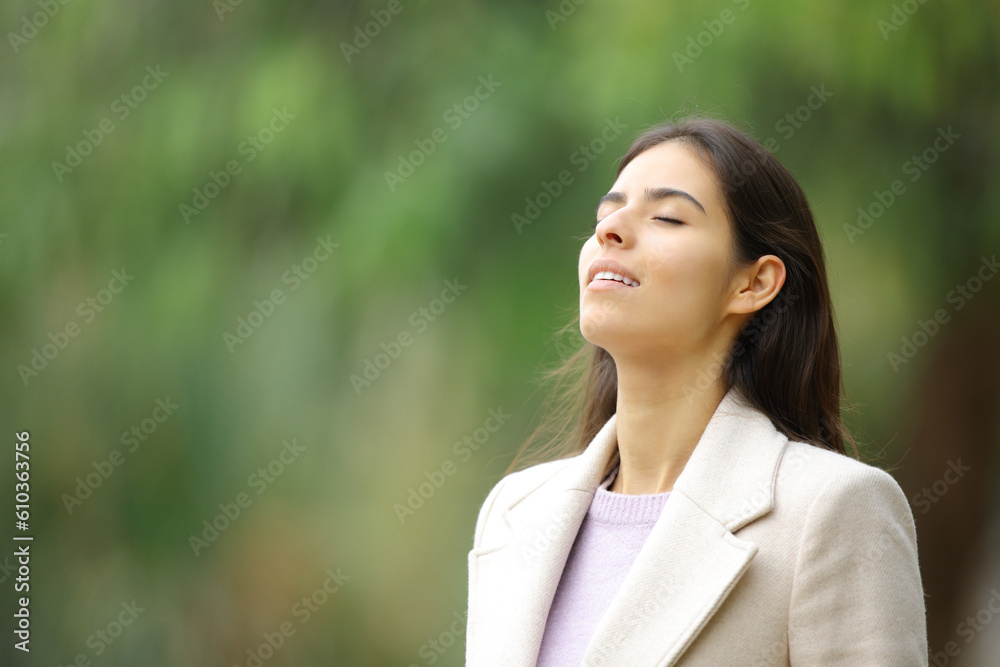 Happy woman breathing in winter in a park