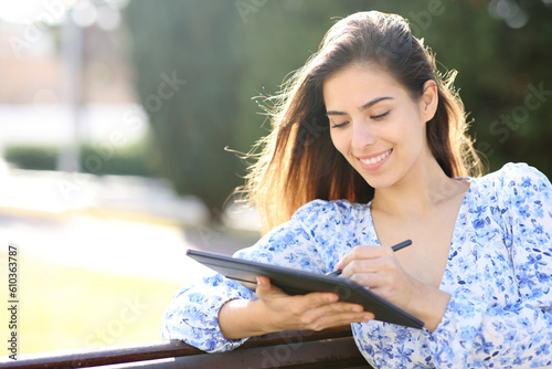 Happy woman writing on tablet with pen photo