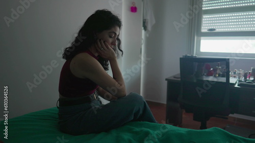 Fotografie One pensive preoccupied young woman sits by bedside with contemplative expression
