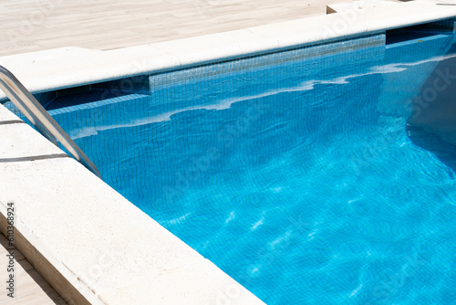 Grab bars ladder in the blue swimming pool