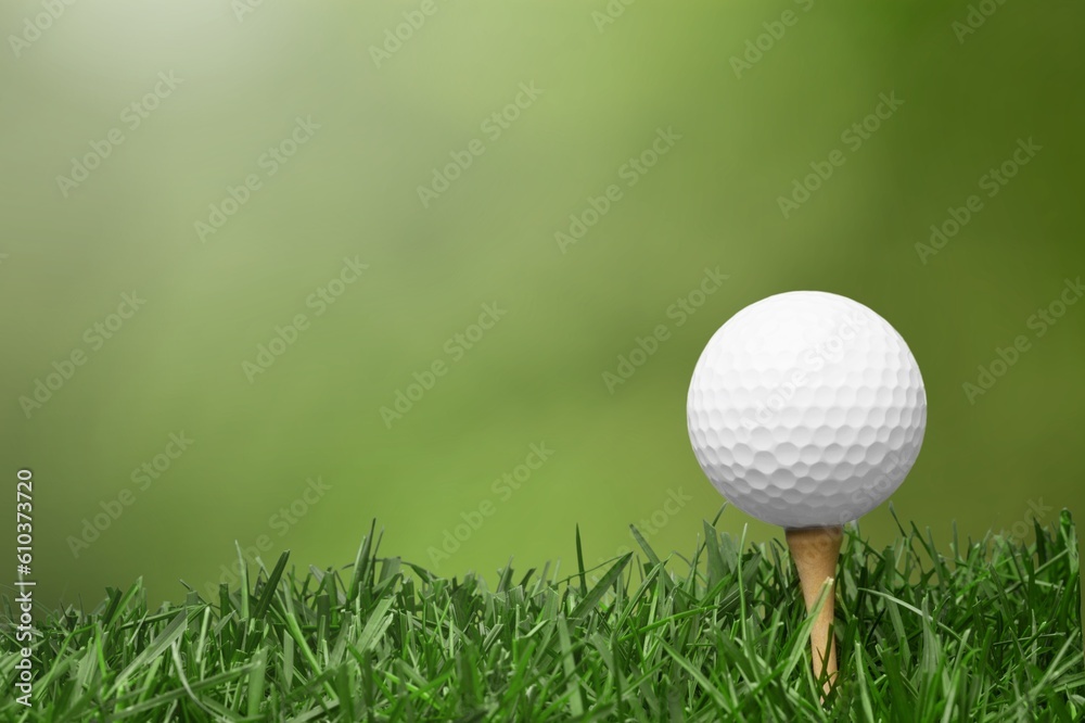White golf ball on wooden tee with grass White golf ball on wooden tee with grass