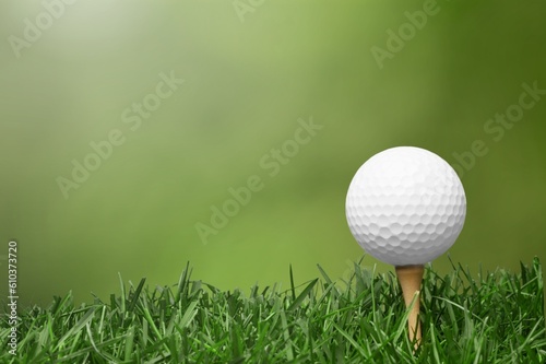 White golf ball on wooden tee with grass