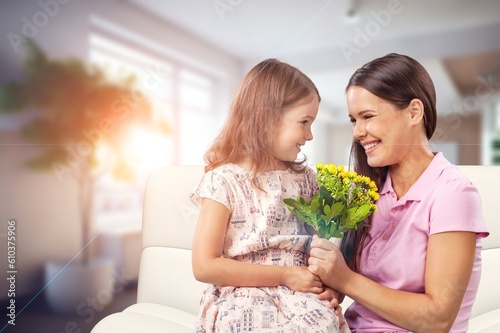 Happy mother and cute daughter gives flowers