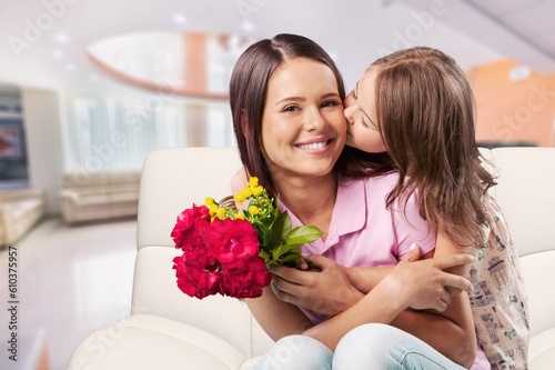Happy mother and cute daughter gives flowers