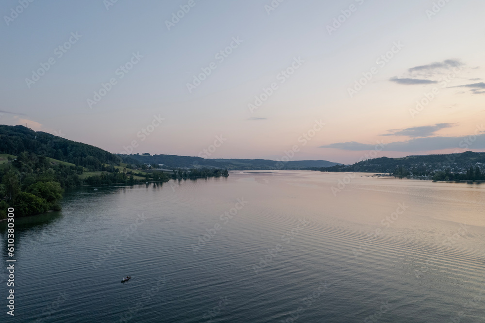 Fototapeta premium aerial footage of sunset over the lake in switzerland and a kayak in the wayer