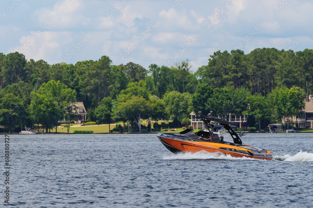 Boater on orange wakeboard ski boat enjoying summer day on the lake.