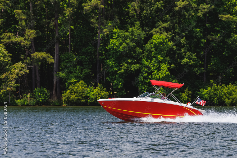 Boater on red power boat enjoying summer day on lake. Power boat cruising on freshwater lake. Boater on red power boat enjoying summer day on lake. Power boat cruising on freshwater lake.