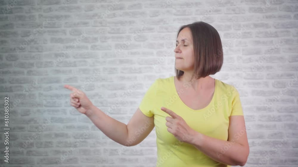 Overjoyed happy woman with open mouth point finger at arm with copy space for promotion isolated over grey studio wall Overjoyed happy woman with open mouth point finger at arm with copy space for promotion isolated over grey studio wall